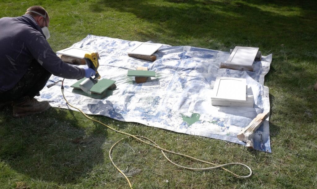 man spraying cabinets with paint sprayer